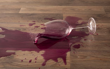 Перевернутый бокал с разлитым красным вином на деревянном полу
